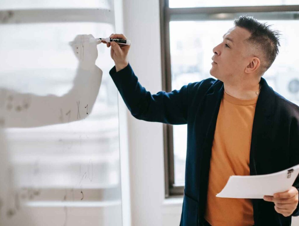 man writing on board